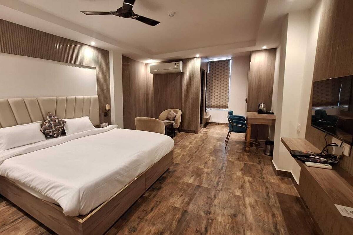 Habitación de hotel moderna con una cama grande, un escritorio, una silla y un televisor.