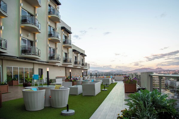 A rooftop terrace with outdoor seating, a green lawn, and a view of the cityscape. - Amaryllis Hotel (Blantyre)