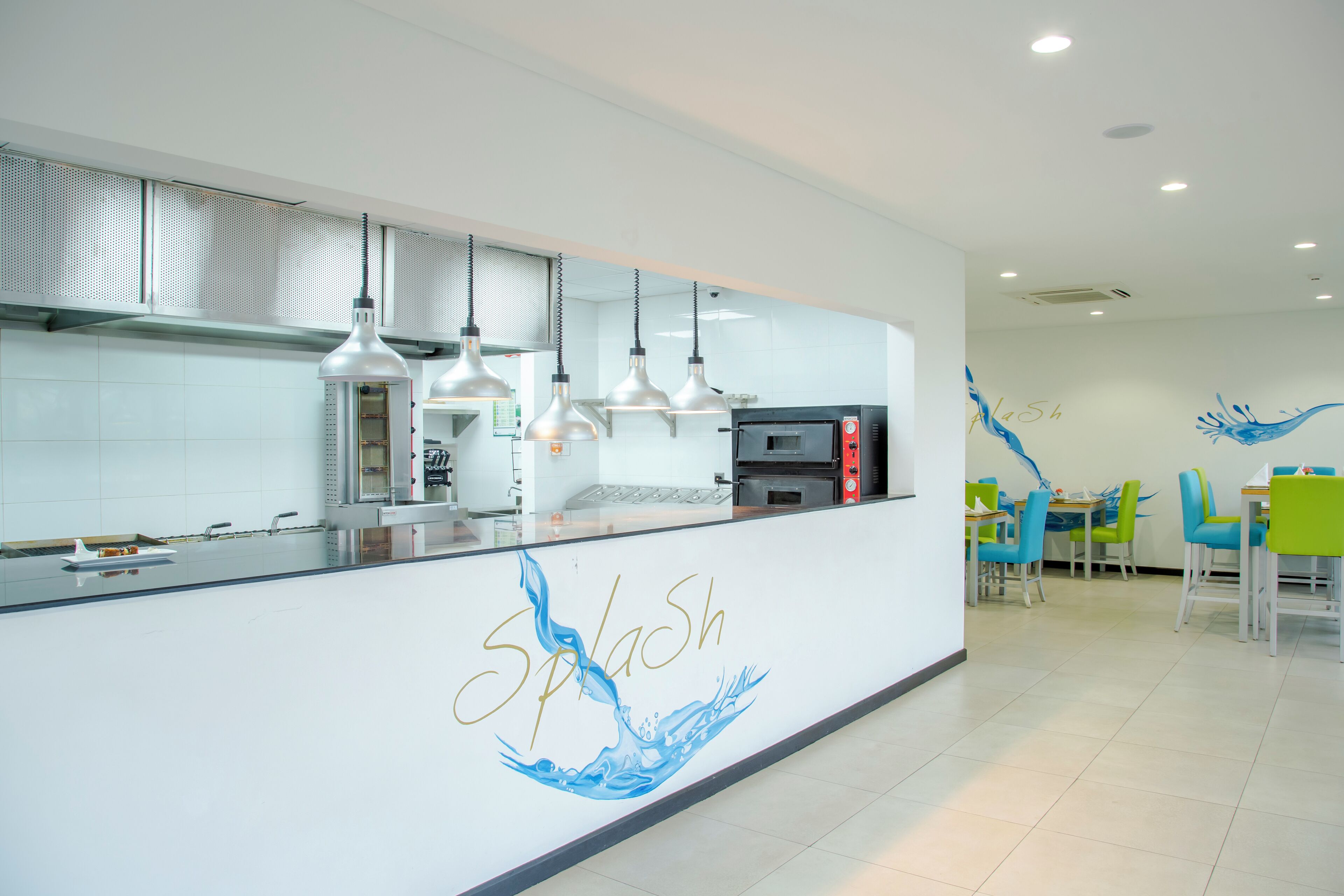 Una cocina moderna con electrodomésticos de acero inoxidable, iluminación colgante y una encimera con el nombre 'Splash'.