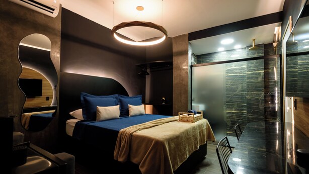 A modern hotel room with a large bed, a bedside table, a mirror, and a bathroom with a glass shower. - NSC 1085 (Rio de Janeiro)