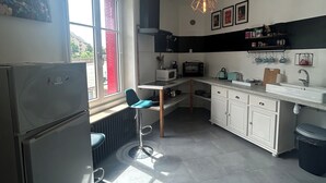 Eine moderne Küche mit Kühlschrank, Mikrowelle und Spüle. Ein Fenster sorgt für natürliches Licht, und ein Stuhl steht in der Nähe.