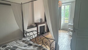 Ein Schlafzimmer mit Himmelbett, Nachttisch, Stuhl und Blick ins Freie.