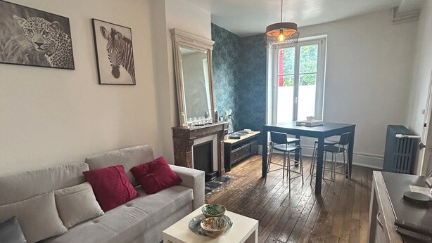 Ein Wohnzimmer mit einer Couch, einem Couchtisch, einem Esstisch mit Stühlen, einem Spiegel und Bildern an der Wand.