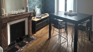 Ein Essbereich mit Holztisch und -stühlen, einem Kamin, einem großen Spiegel und einer Pendelleuchte.