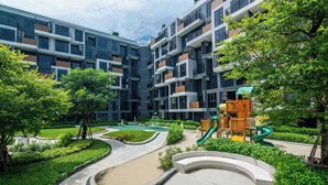 A modern apartment complex with a playground, green spaces, and a curved pathway. - Skypark Aurora,  Studio 1711 1A Premium (Choeng Thale)