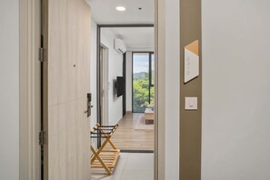 A modern interior with a wooden bench, a flat-screen TV, and a view of greenery outside.