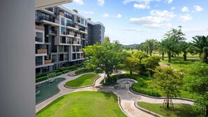Un immeuble d’appartements moderne doté de nombreux balcons et d’une cour bien entretenue, agrémentée de verdure et d’une aire de jeux.
