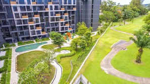 A modern apartment building with a playground, green spaces, and a golf course. - Skypark Aurora, One Bedroom 2312 1B Deluxe (Choeng Thale)