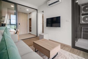 Una sala de estar moderna con un sofá, una mesa de centro y un televisor montado en la pared.