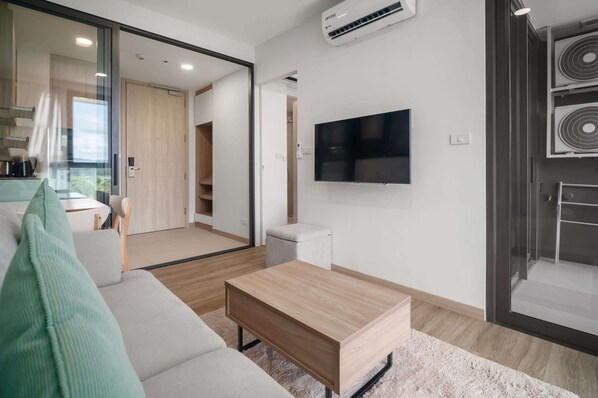 A modern living room with a sofa, a coffee table, and a TV mounted on the wall.