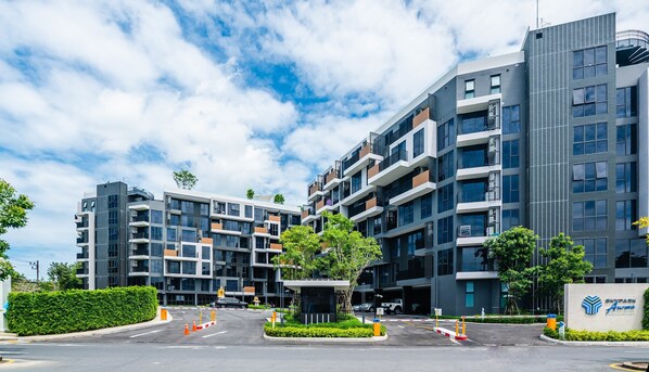 Un immeuble moderne à plusieurs étages, doté d’un parking, d  ’un panneau indiquant un « Skypark » et offrant une vue sur un ciel dégagé.