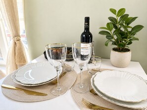 A table set with white plates, gold-rimmed glasses, and a bottle of Saint Marc wine.