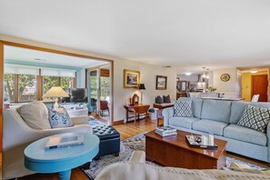 A spacious living area with a sofa, coffee table, and a dining area with a table and chairs.