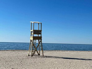 En redningsplatform på en strand med klare himmel og roligt vand.