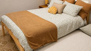 A bedroom with a bed, a nightstand, a lamp, and a window with blinds.