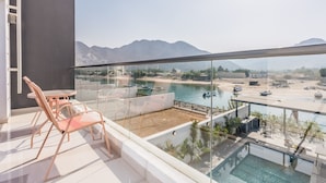 Ein Balkon mit Glasgeländer, der Blick auf Strand und Berge freigibt.