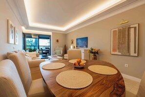 Ein modernes Wohnzimmer mit einem Holzesstisch, beigefarbenen Sofas und Kunstwerken an den Wänden.