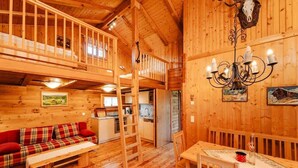 A wooden cabin interior with a loft bedroom, a dining area, and a kitchen. - Lima Alpine Lodges - Almhaus Theresia (Sauerwald)