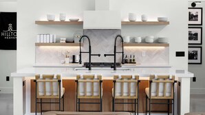 A modern kitchen with a central island, bar stools, pendant lighting, and a herringbone-patterned backsplash. - Labor Day Getaway | Heated Pool + Spa + Epic Views (Canyon Lake)