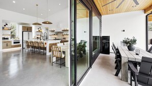 A modern kitchen with a central island, wooden ceiling, and a dining area with a large table and chairs. - Labor Day Getaway | Heated Pool + Spa + Epic Views (Canyon Lake)