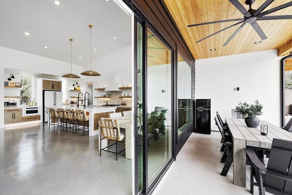 A modern kitchen with a central island, wooden ceiling, and a dining area with a large table and chairs.