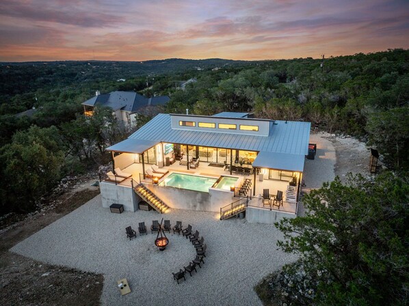 Une maison moderne dotée d’une piscine, d’un espace salon extérieur et offrant une vue sur le paysage environnant.
