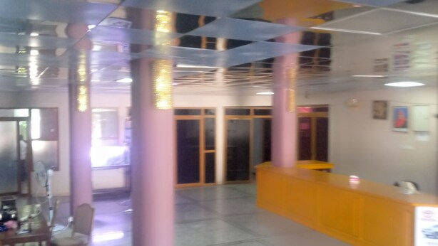 A reception area with a counter, chairs, and a tiled floor. - FAVOURED HOTEL (Mwanza)