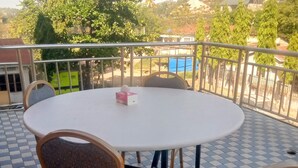 A round table with four chairs on a checkered floor, overlooking a scenic view with trees and buildings. - FAVOURED HOTEL (Mwanza)