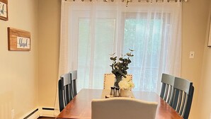 A dining room with a wooden table, four chairs, a chandelier, and a window with sheer curtains. - Charming 3-bedroom house with WiFi and AC in beautiful Richmond (Richmond)