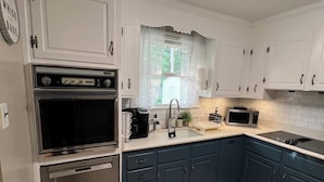 A modern kitchen with white cabinets, a Bosch dishwasher, a built-in oven, a microwave, and a sink. - Charming 3-bedroom house with WiFi and AC in beautiful Richmond (Richmond)