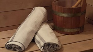 A wooden bench with two rolled towels and a wooden bucket with a wooden spoon. - Wellness-Loft: sauna, jacuzzi&  cinema. Centrally located near the station (Bodegraven)
