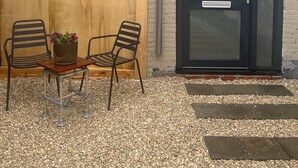 A wooden fence, two metal chairs, a small table with a potted plant, and a black door with a peephole. - Wellness-Loft: sauna, jacuzzi&  cinema. Centrally located near the station (Bodegraven)