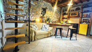 Un espacio de sala acogedor con un sofá, un estante de madera, una cocina con pared de ladrillo y un refrigerador amarillo.