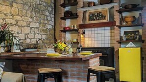 Una cocina rústica con paredes de ladrillo visto, vigas de madera y un refrigerador amarillo.
