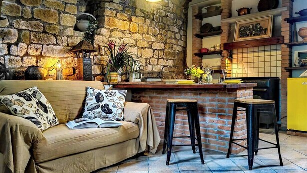 Un salón acogedor con una pared de piedra, una barra de madera y un armario amarillo.