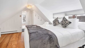 A bedroom with a bed, a window, and a door.