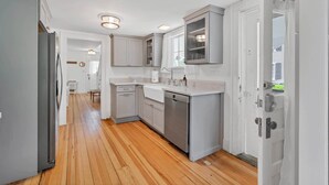 A modern kitchen with grey cabinets, a dishwasher, and a built-in oven.