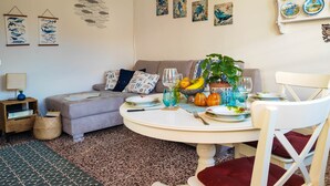 Un coin repas comprenant une table ronde, des chaises, un canapé et un mur décoré d’assiettes et d’œuvres d’art.