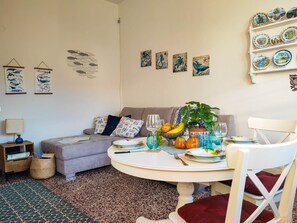 Un comedor con una mesa redonda, sillas, un sofá y una pared decorada con platos y obras de arte.