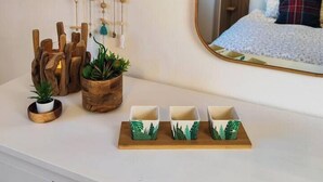 Une chambre à coucher avec un lit, une table de chevet agrémentée d’objets décoratifs, un mobile à vent fixé au mur et un miroir qui reflète la pièce.