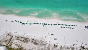 An aerial view of a beach with rows of umbrellas and beachgoers. - Rare Front Stack Remodeled 2 bedroom Gem in Mainsail- Free Beach Service! (Miramar Beach)