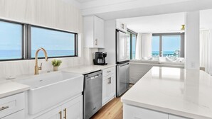 A modern kitchen with white cabinetry, stainless steel appliances, and a view of the ocean. - Rare Front Stack Remodeled 2 bedroom Gem in Mainsail- Free Beach Service! (Miramar Beach)