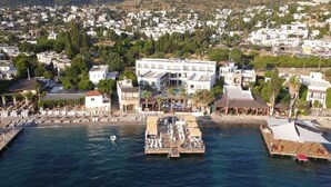 Un pueblo costero con un puerto deportivo, edificios blancos y un muelle con barcos.