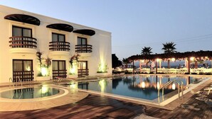 Un hotel con piscina, terraza de madera y un edificio con balcones.