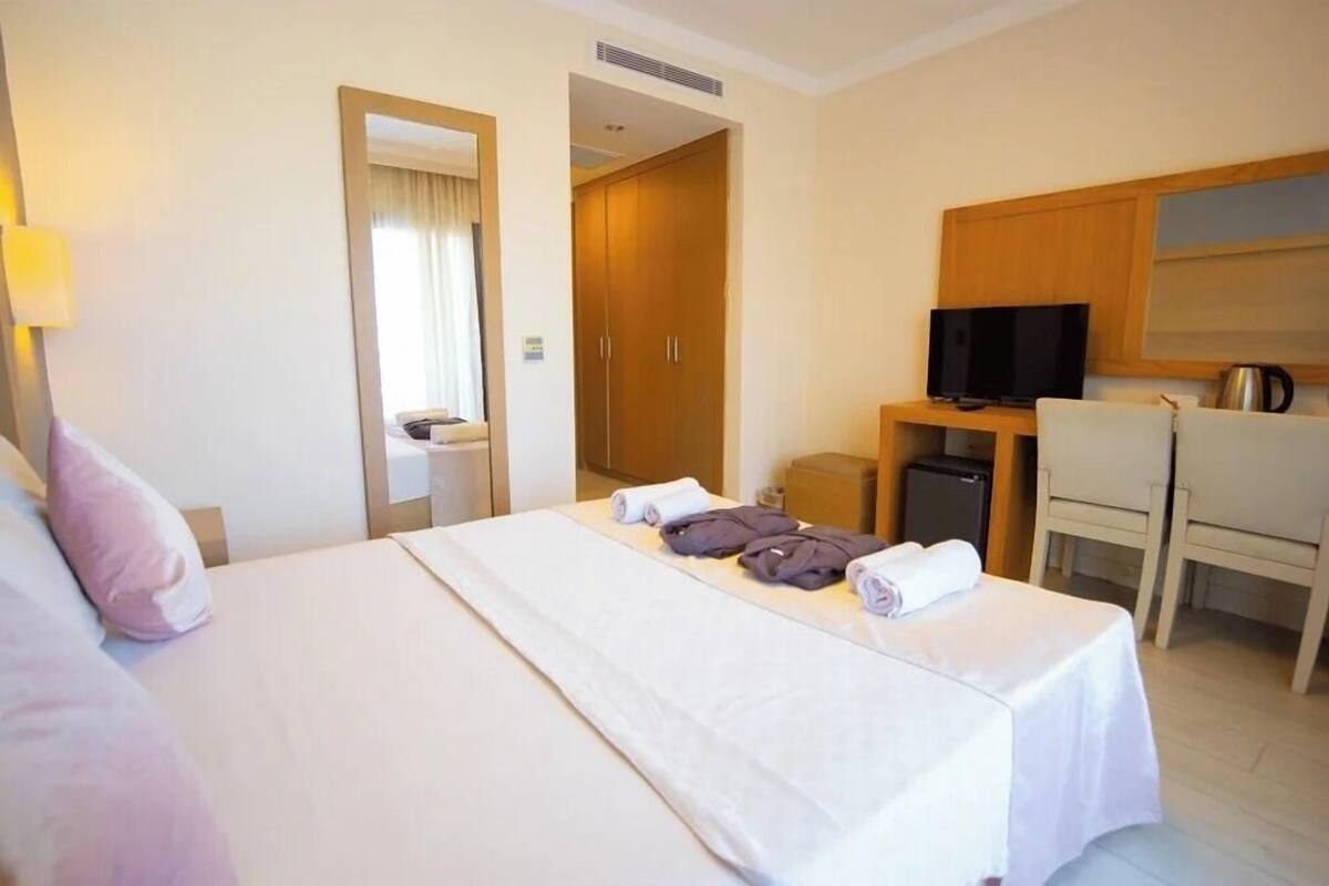 Habitación de hotel con cama, escritorio con televisor, silla y kitchenette.