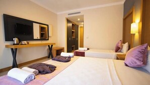 Una habitación de hotel con dos camas, televisión, escritorio y espejo.