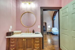 A bathroom with a large mirror, a vanity with a sink, and a wooden cabinet with drawers. - Heart of Downtown Marshall: Boutique Studio Stay! (Marshall)
