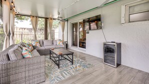 A covered patio with a wicker sofa, a coffee table, and a built-in grill.