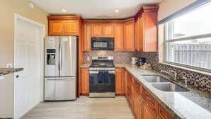 A kitchen with wooden cabinets, stainless steel appliances, a double sink, and a window with a view.