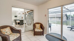 A room with a sliding glass door leading to a balcony, a wicker chair, and a dining area with a table and chairs. - 2 Mi to Beach: Home w/ Pool in Venice (Venice)